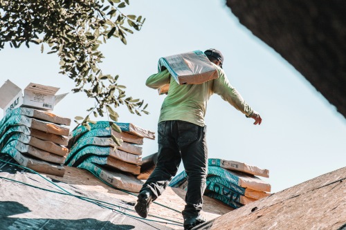 Contractor carrying building materials to apply a new roof