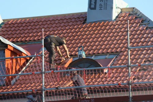 Male Contractor on Scaffolding installing a new roof on a residential building